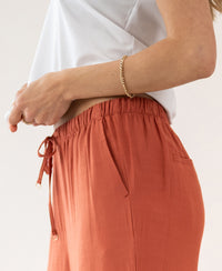 Person wears terra-colored wide-leg pants with elastic waist.