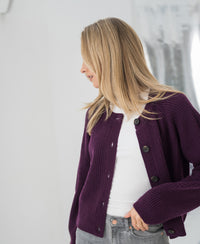 Side view of a woman wearing a PLEIN PUBLIQUE merino wool vest in Cassis color, hand in pocket.