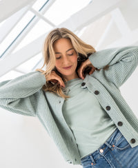 Woman wearing a light green merino wool vest, front view.