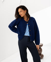 Woman wearing a navy merino wool vest, smiling with one hand on her hip.