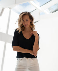 Black linen T-shirt from PLEIN PUBLIQUE, LA DOMI style, shown in a sunlit room.