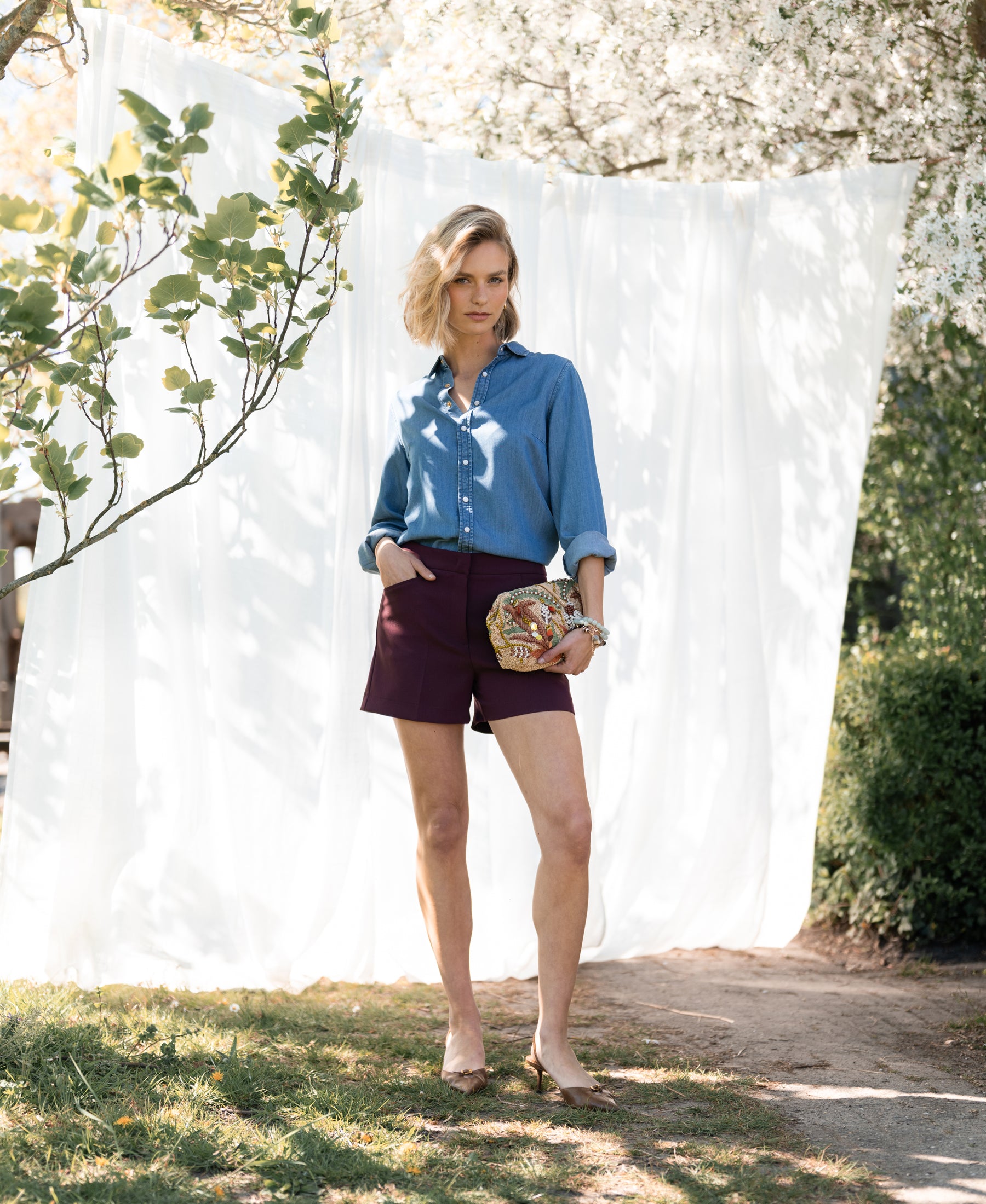 Bordeaux-colored short skirt shown outdoors under blooming tree.