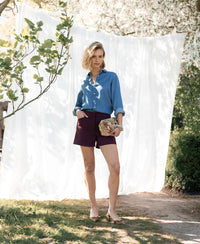 Bordeaux-colored short skirt shown outdoors under blooming tree.