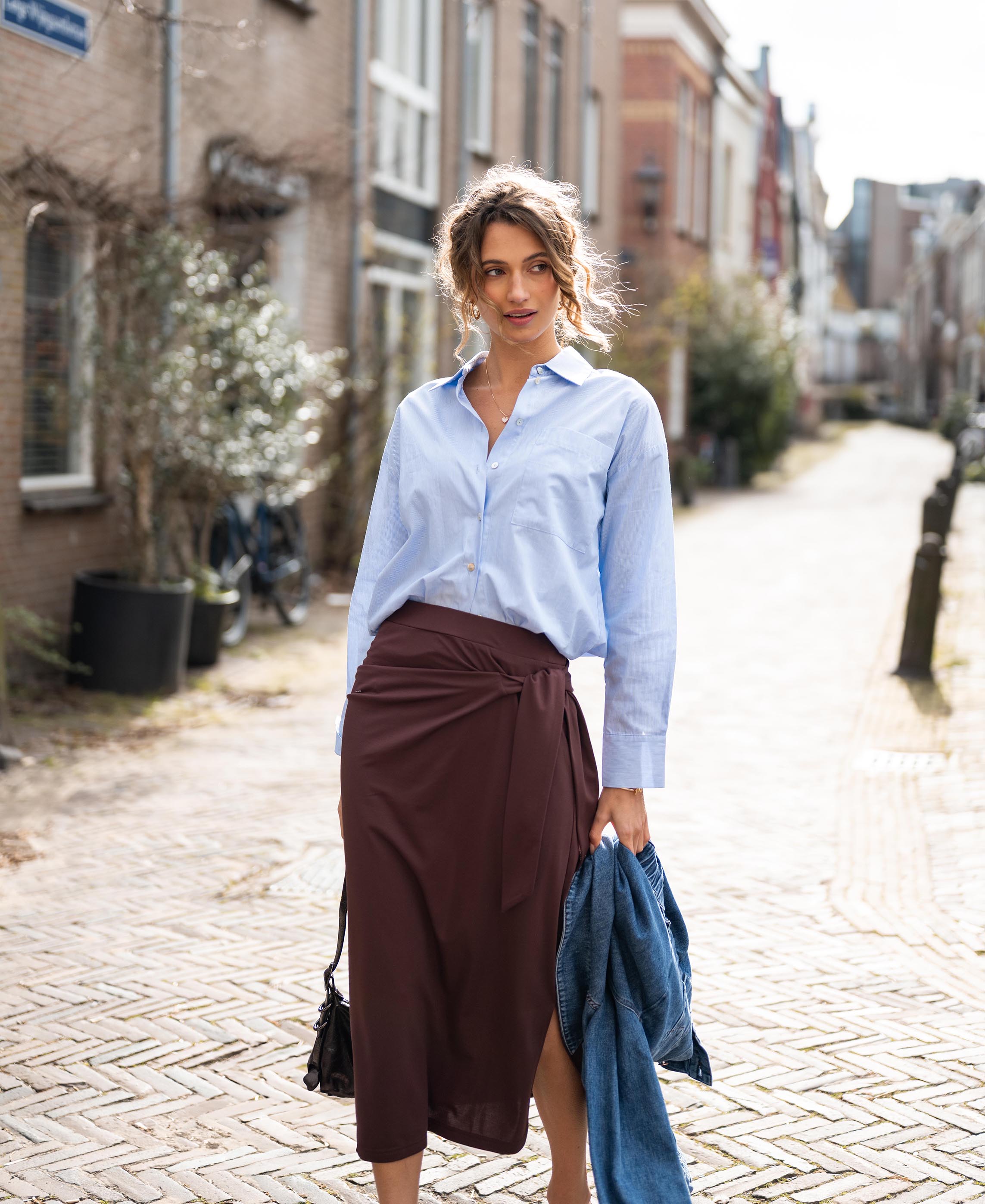 Woman wearing the Plein Publique travel skirt Le Mael in cacao brown, standing on a cobblestone street.