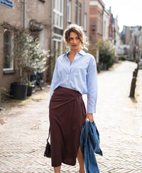 Woman wearing the Plein Publique travel skirt Le Mael in cacao brown, standing on a cobblestone street.