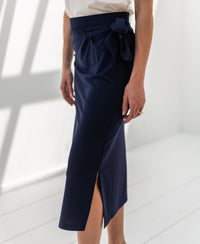 Navy blue LE MAEL travel skirt by PLEIN PUBLIQUE shown against a bright background with white floors and walls.