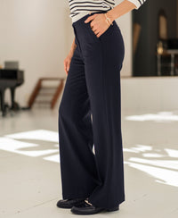 Person wears dark blue pinstripe trousers, hands in pockets.