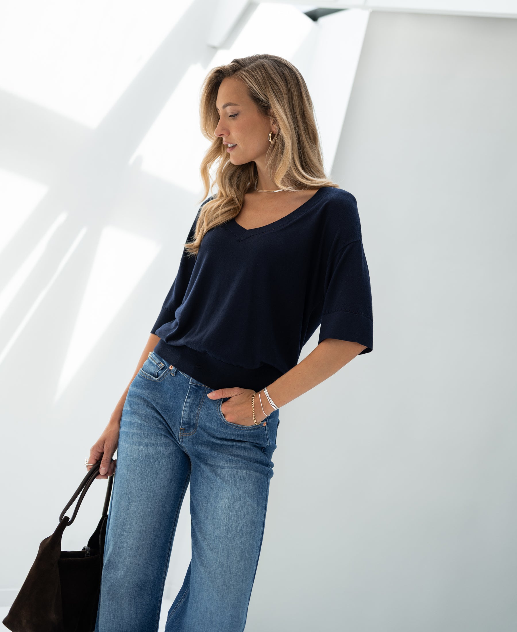 Woman wearing a dark blue silk blend top by PLEIN PUBLIQUE in modern lighting.