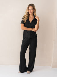 Charcoal Lounge Pants LE HUGO by PLEIN PUBLIQUE, shown on a person standing by a light beige wall.