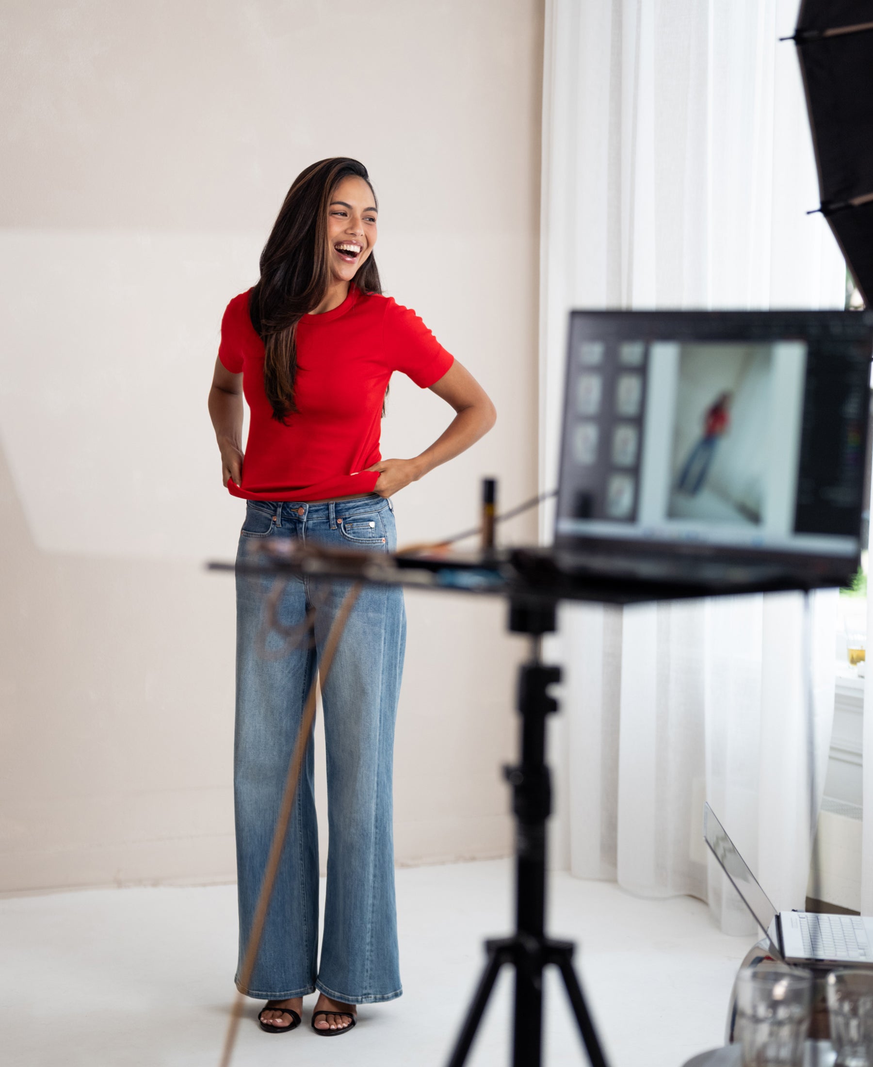 Woman wears a luxe, soft, red LA MASSY T-shirt by PLEIN PUBLIQUE, photographed in a bright studio.