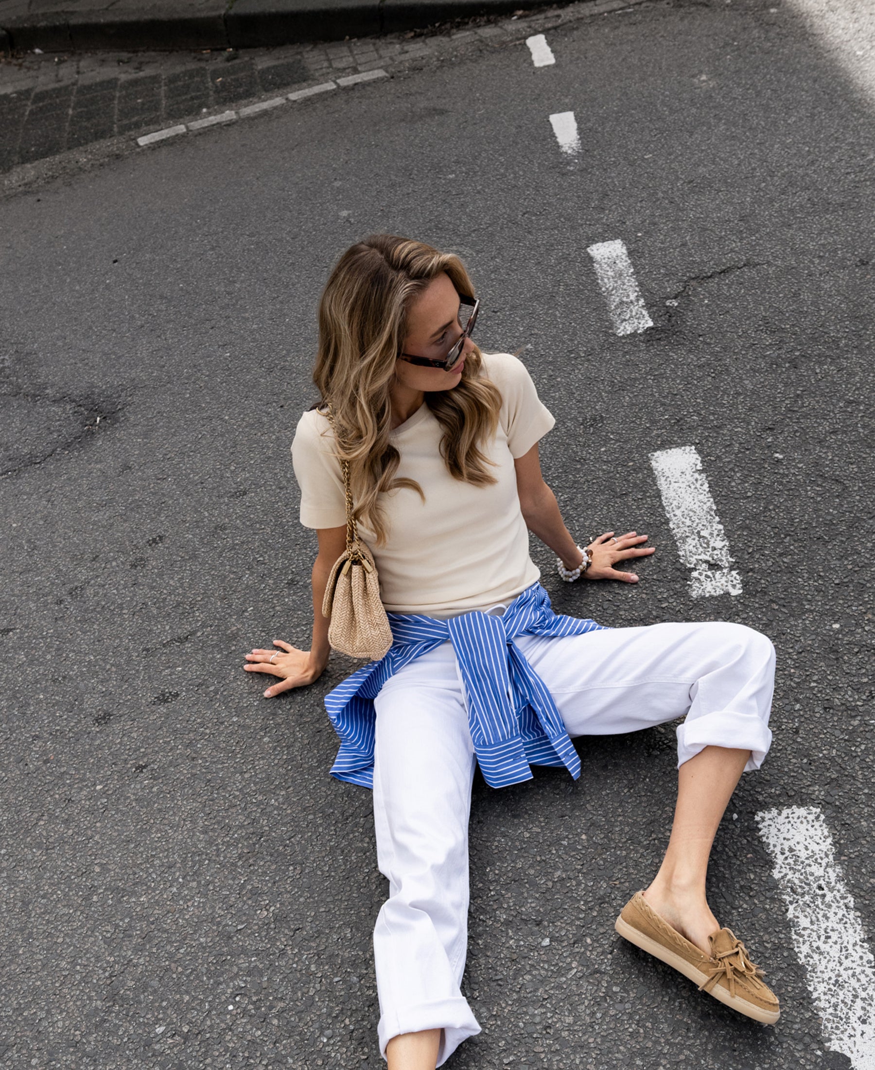 Woman wearing white cropped jeans on the road.