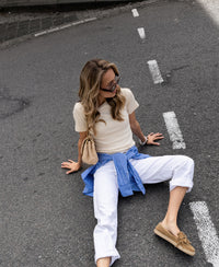 Woman wearing white cropped jeans on the road.