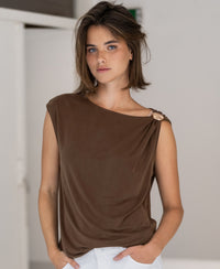 Woman with short brown hair wearing the PLEIN PUBLIQUE brown top with buckle, standing indoors.