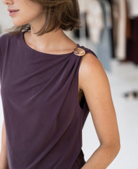 Woman wearing a PLEIN PUBLIQUE wine-colored top with a gold shoulder button.