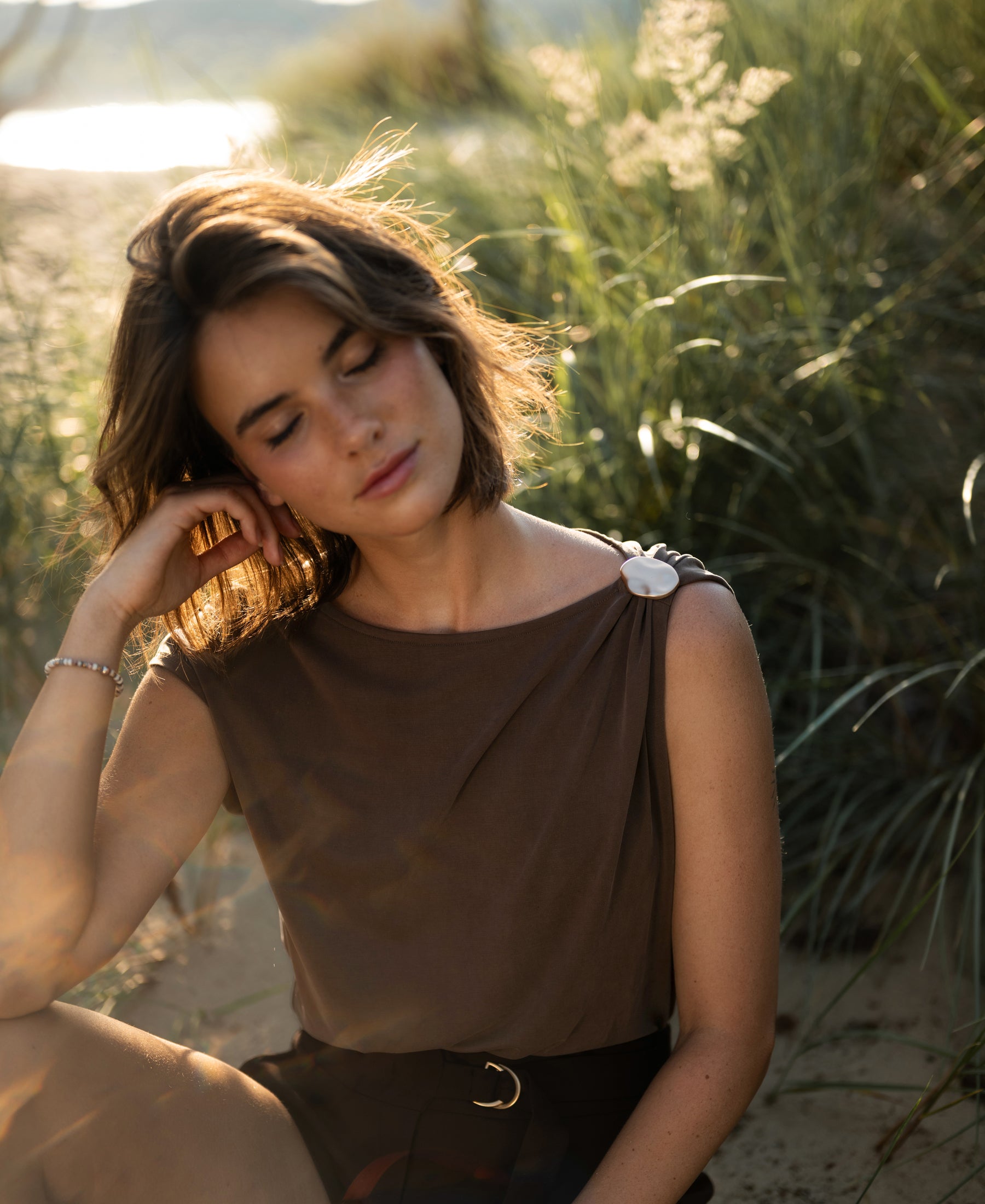 Brown LA MAYA top with buckle by PLEIN PUBLIQUE shown outdoors.