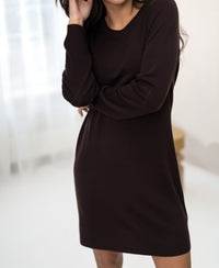 Brown merino wool LA MIMI dress by PLEIN PUBLIQUE shown indoors by sheer white curtains.