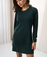 Woman modeling PLEIN PUBLIQUE merino wool dress in dark green indoors.