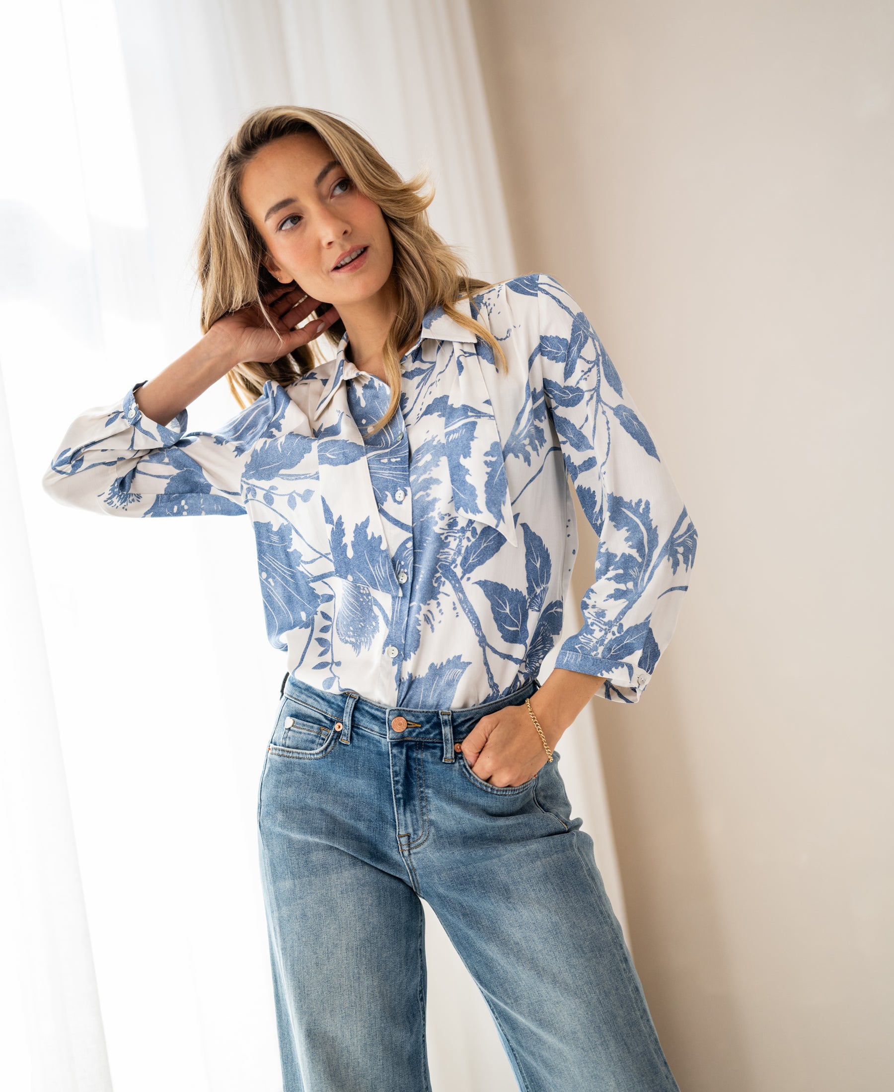 Woman wears floral print blouse with tie detail in XL, indoors.