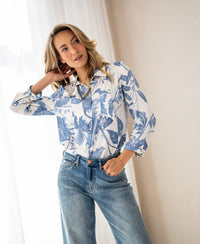 Woman wears floral print blouse with tie detail in XL, indoors.