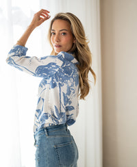 XL floral print blouse with tie detail, shown from the back by a woman gazing over her shoulder near a window.