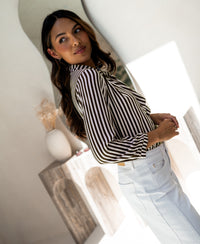 PLEIN PUBLIQUE LA MINOU ivory-cacao striped blouse with tie detail shown in a bright, modern room.