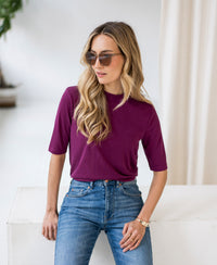 Woman wears the PLEIN PUBLIQUE ribbed magenta collared top indoors.
