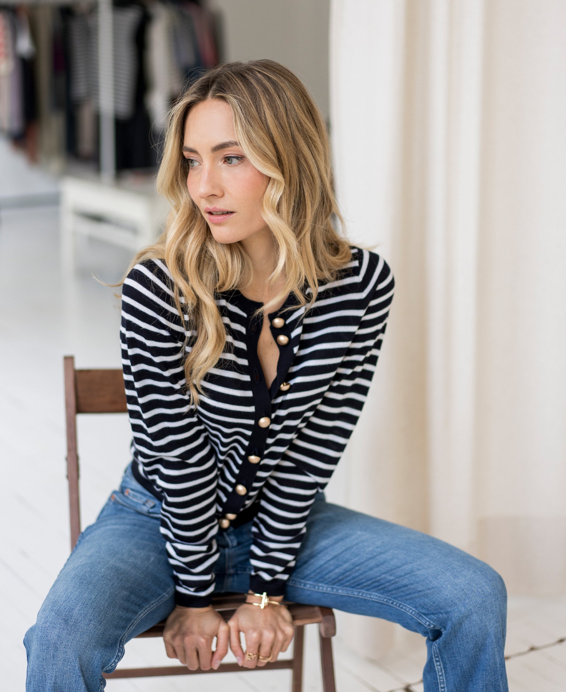 Woman wearing a PLEIN PUBLIQUE striped cardigan LA MONACO, looking thoughtfully to the side.
