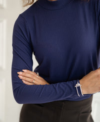 Woman wearing an indigo bamboo top, LA MONTAGNE style by PLEIN PUBLIQUE, arms crossed.