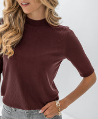 Woman wears ribbed collared top in cacao brown.
