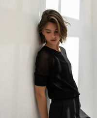 Black mesh sweater with silk by PLEIN PUBLIQUE, shown from the front against a white wall.