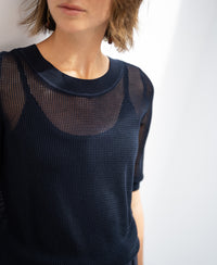 Dark blue mesh sweater with silk, shown on a woman standing by a white wall.