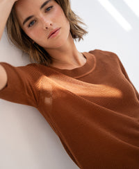 Havana mesh sweater LE NANCY in beige shown on a model leaning against a white wall, front view.