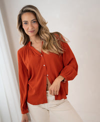 Burnt orange LA NIMES blouse by PLEIN PUBLIQUE, worn by woman with long hair.