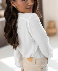White LA NIMES blouse by PLEIN PUBLIQUE shown from the back, worn indoors.