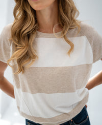 Woman wearing PLEIN PUBLIQUE striped sweater LA PALOISE in sand-ivory, hands behind back.