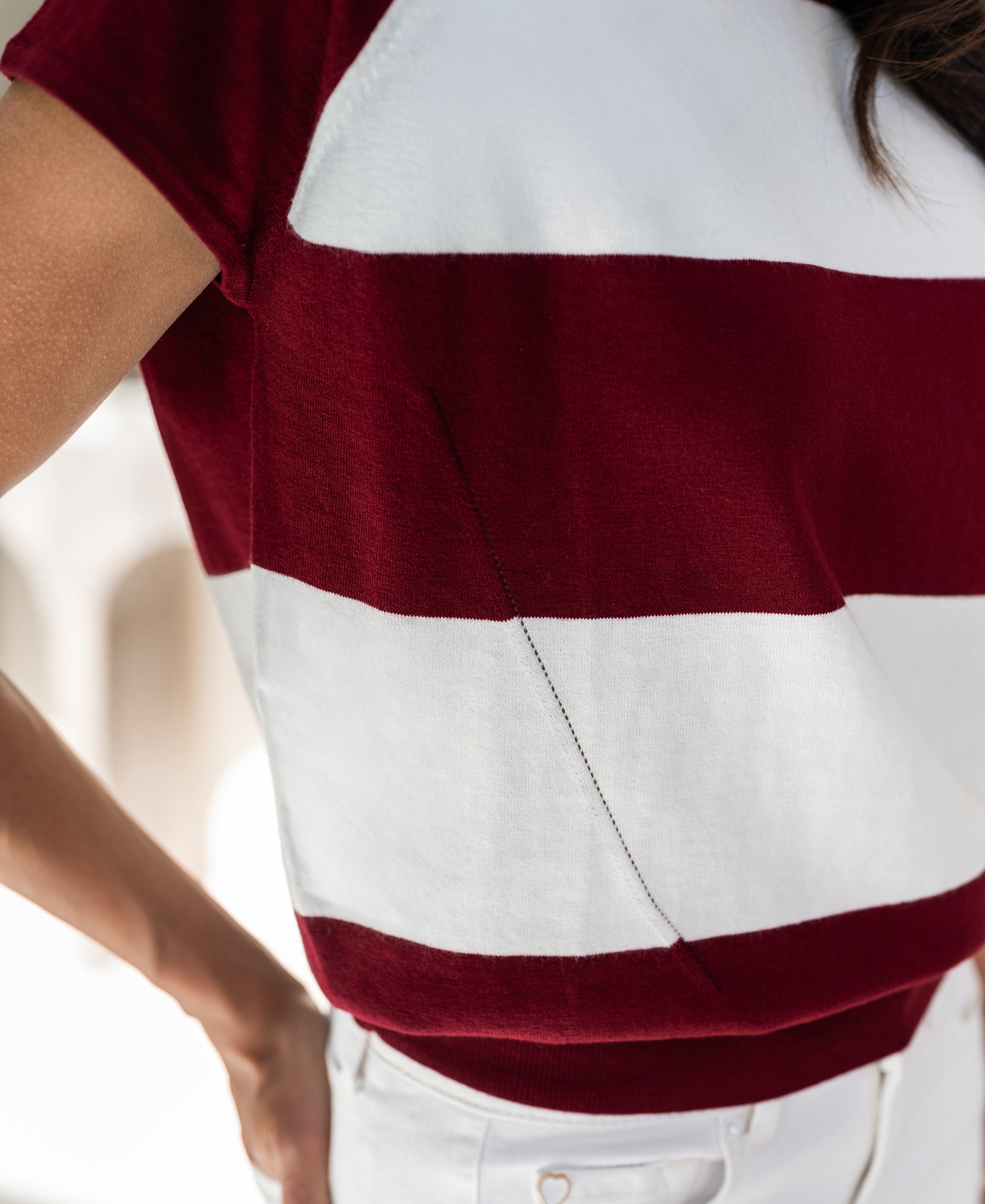 Side view of model wearing a striped PLEIN PUBLIQUE LA PALOISE sweater in wine-ivory.