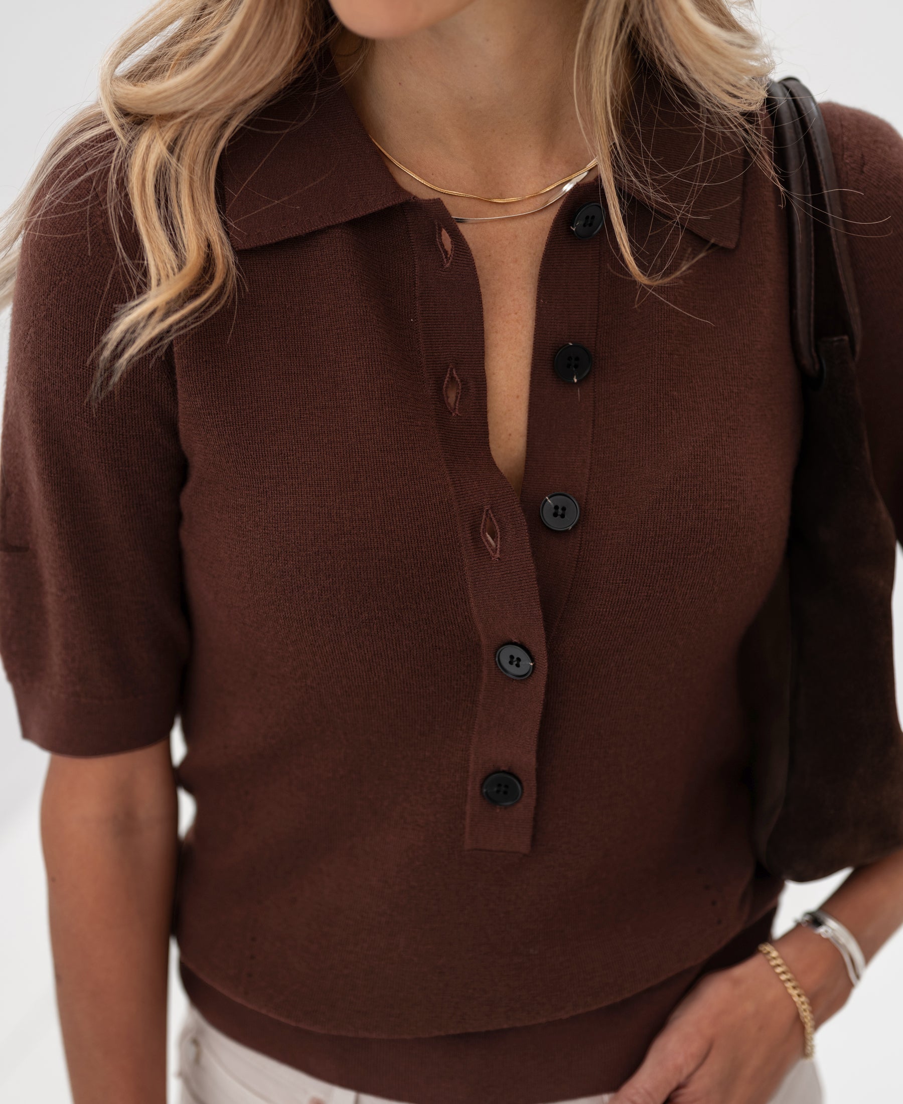 Woman wearing the Plein Publique merino wool polo shirt in cocoa brown.