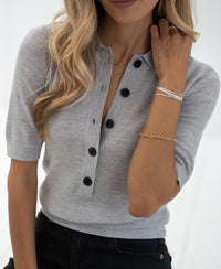 Woman wears a silver-grey merino wool polo shirt from PLEIN PUBLIQUE, shown from the front.