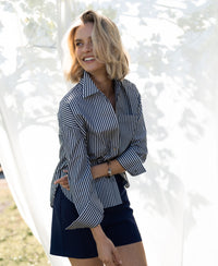 Striped white and anthracite Plein Publique LA PASCALLE blouse shown outdoors before a white backdrop.