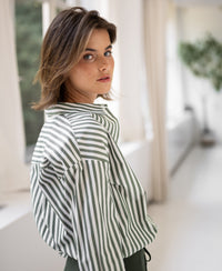 Striped white and olive green blouse by PLEIN PUBLIQUE, model seen from the back, looking over her shoulder.