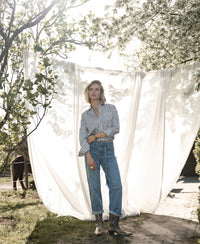 Striped white and olive green Plein Publique LA PASCALLE blouse displayed outside by a white curtain.