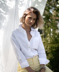 White striped blouse with a tone-on-tone design, worn outdoors.