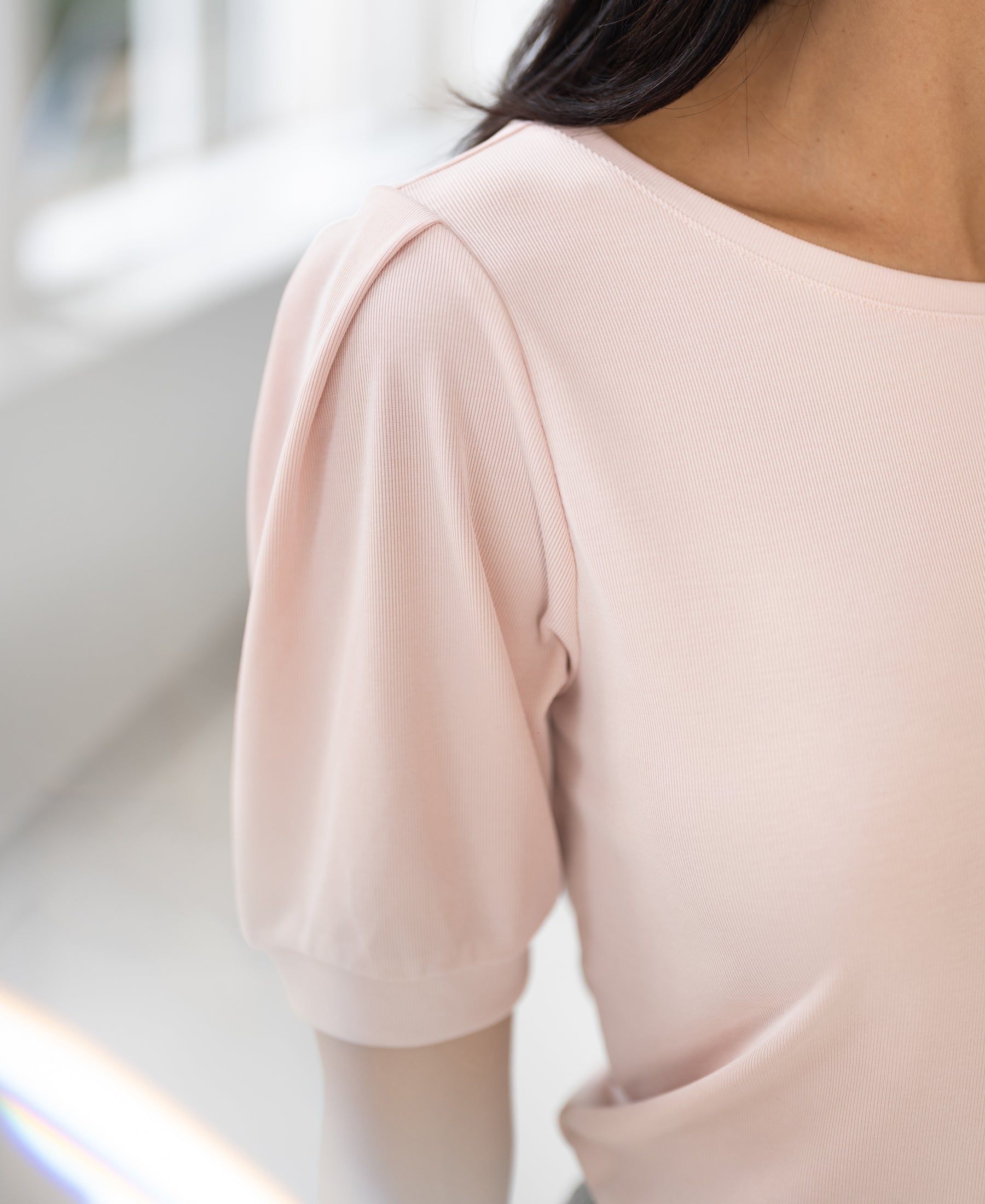 Blush ribbed T-shirt shown from shoulders down in bright indoor light.