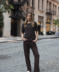 Chocolate brown ribbed T-shirt in a relaxed fit, shown outdoors with hands in pockets.