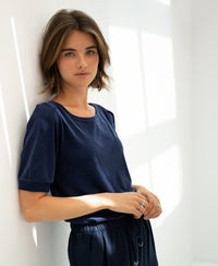Woman wearing a dark blue ribbed T-shirt, sunlight streaming in.
