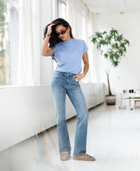 Woman wears light blue ribbed collared top from PLEIN PUBLIQUE, photographed indoors.