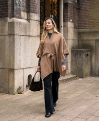 Woman wearing a camel-colored merino wool poncho.