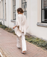 Light sand-colored merino wool poncho by Plein Publique, shown on a woman.