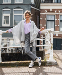 Light grey merino wool poncho in a relaxed fit, shown on a model outdoors.