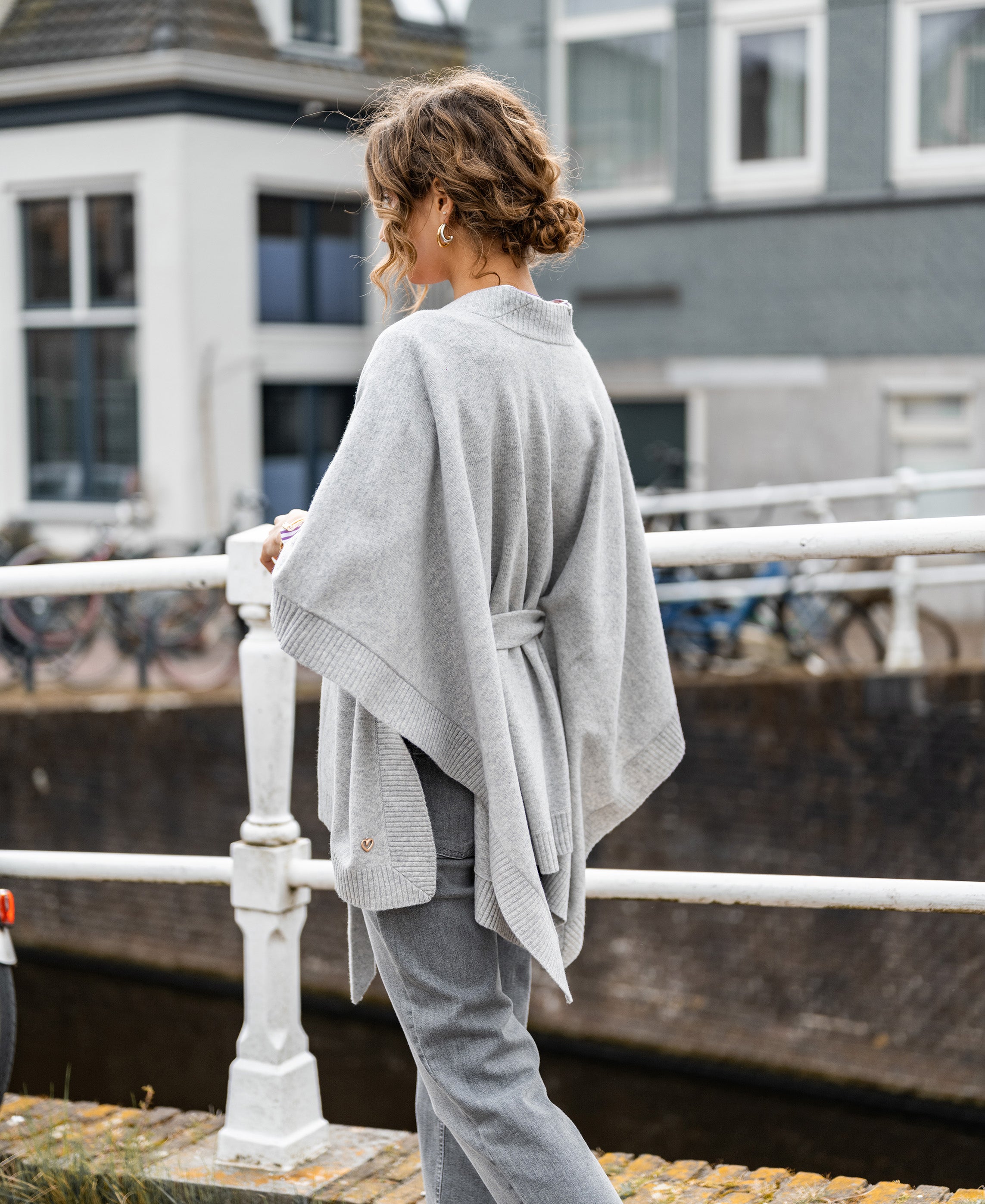 Woman wearing a Plein Publique merino wool poncho in silver gray.